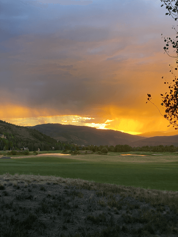 A golf course at sunset with a rainstorm in the distance in Vail, Colorado.